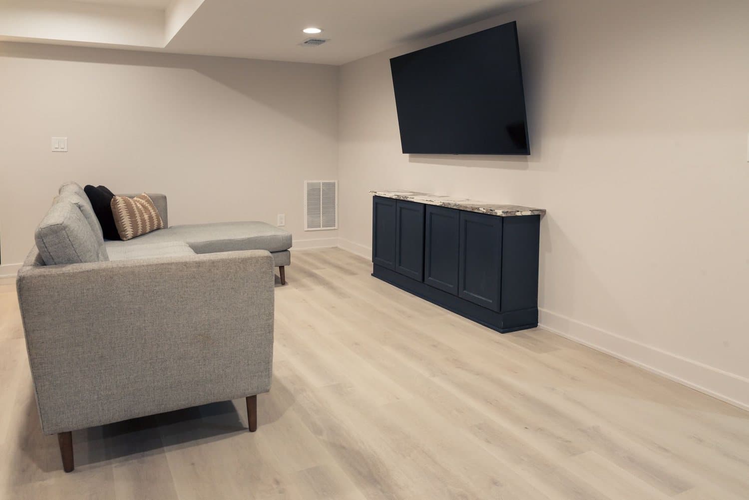 Finished basement family room with a sofa and wall-mounted TV