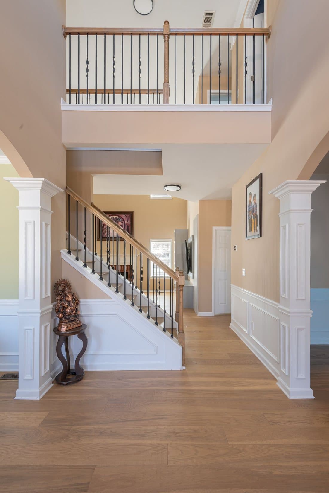 Bright finished basement foyer with a white staircase and wood floors